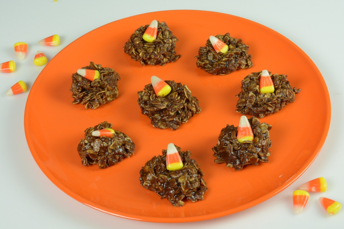 An orange plate of chocolate Uncooked Dainties each with an orange and yellow candy corn on top.