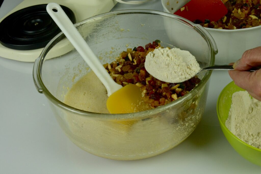 A mixer bowl with the wet ingredients, fruit-nut mixture and flour about to be stirred in.