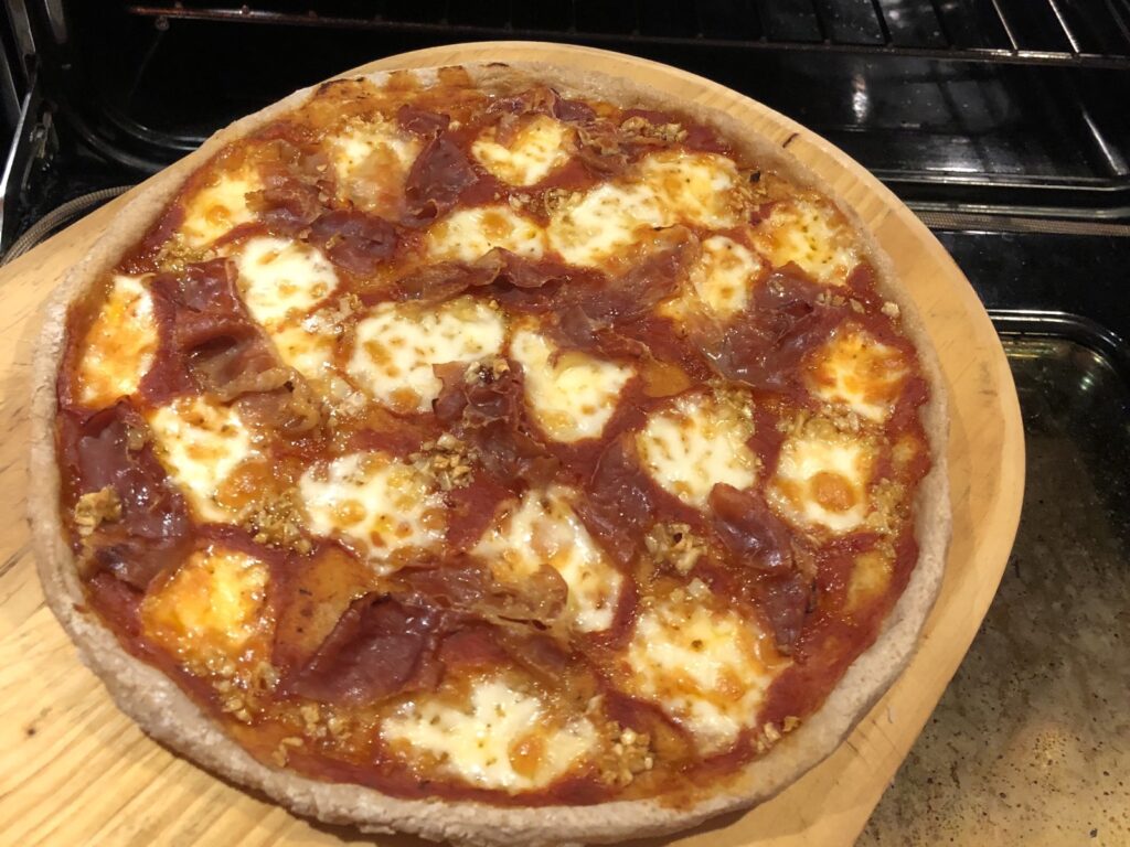 California Pizza on a pizza board in front of an open oven.