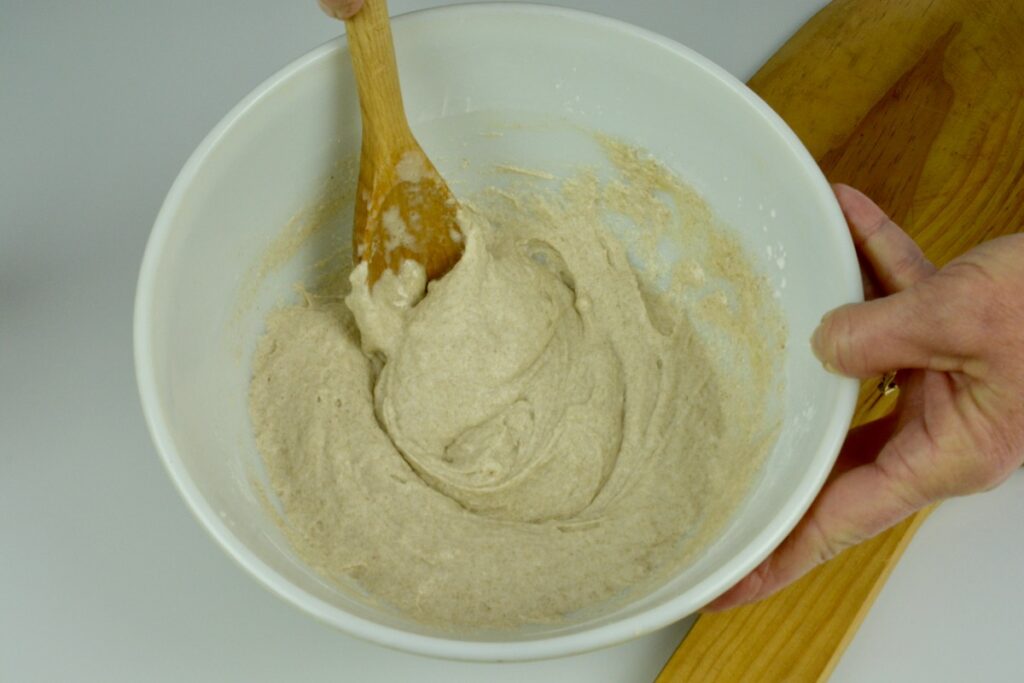 A bowl of just mixed wet and dry ingredients for pizza dough that looks like batter.