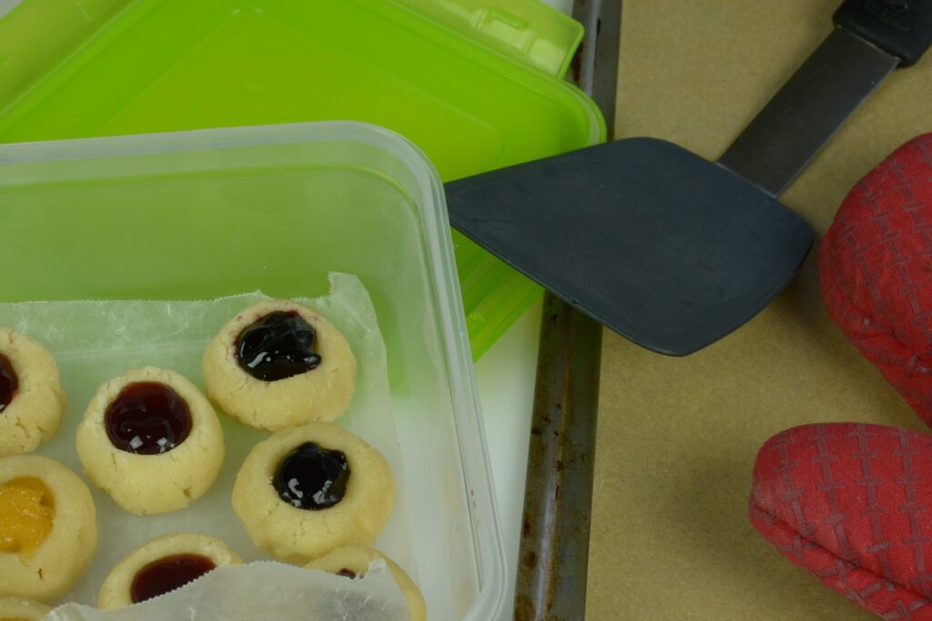 Raw Jam Thumbprint Cookies in a plastic container to go in the freezer.