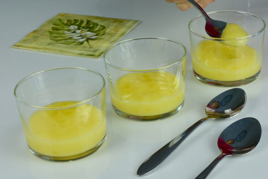 Three dishes of Lemon Curd with a hand taking a spoonful out of one.
