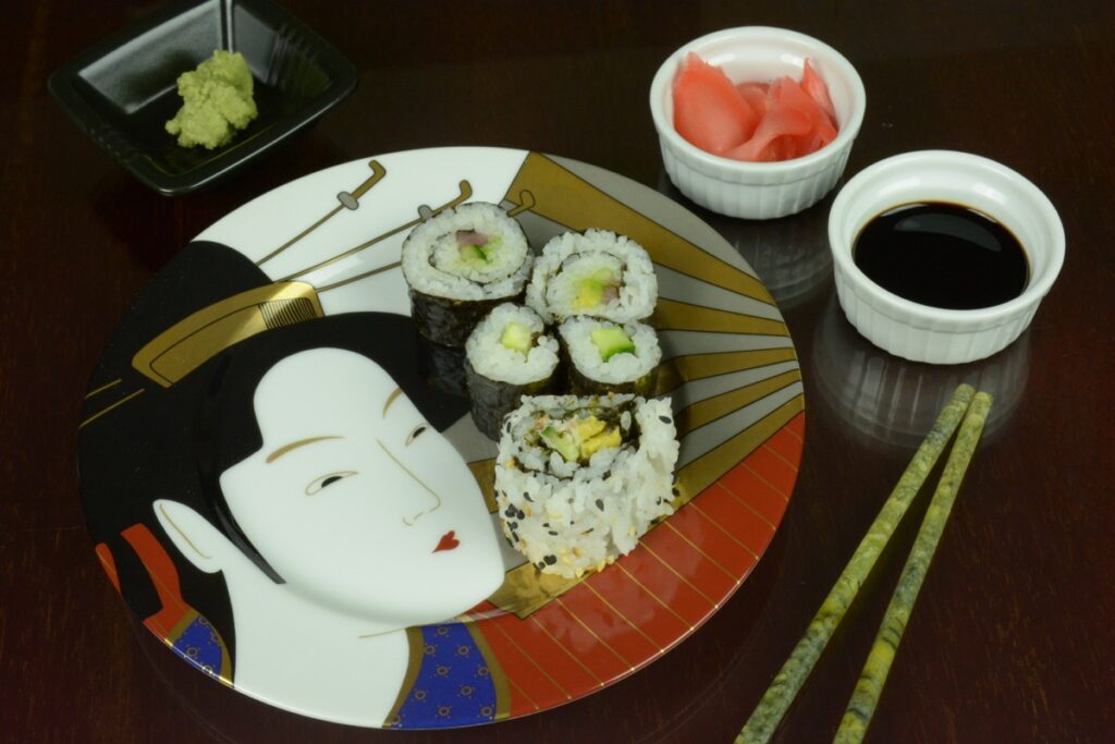 A Japanese plate with sushi rolls surrounded by wasabi paste, pickled ginger and soy sauce.