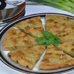 A plate of Chinese Onion Bread cut into wedges.