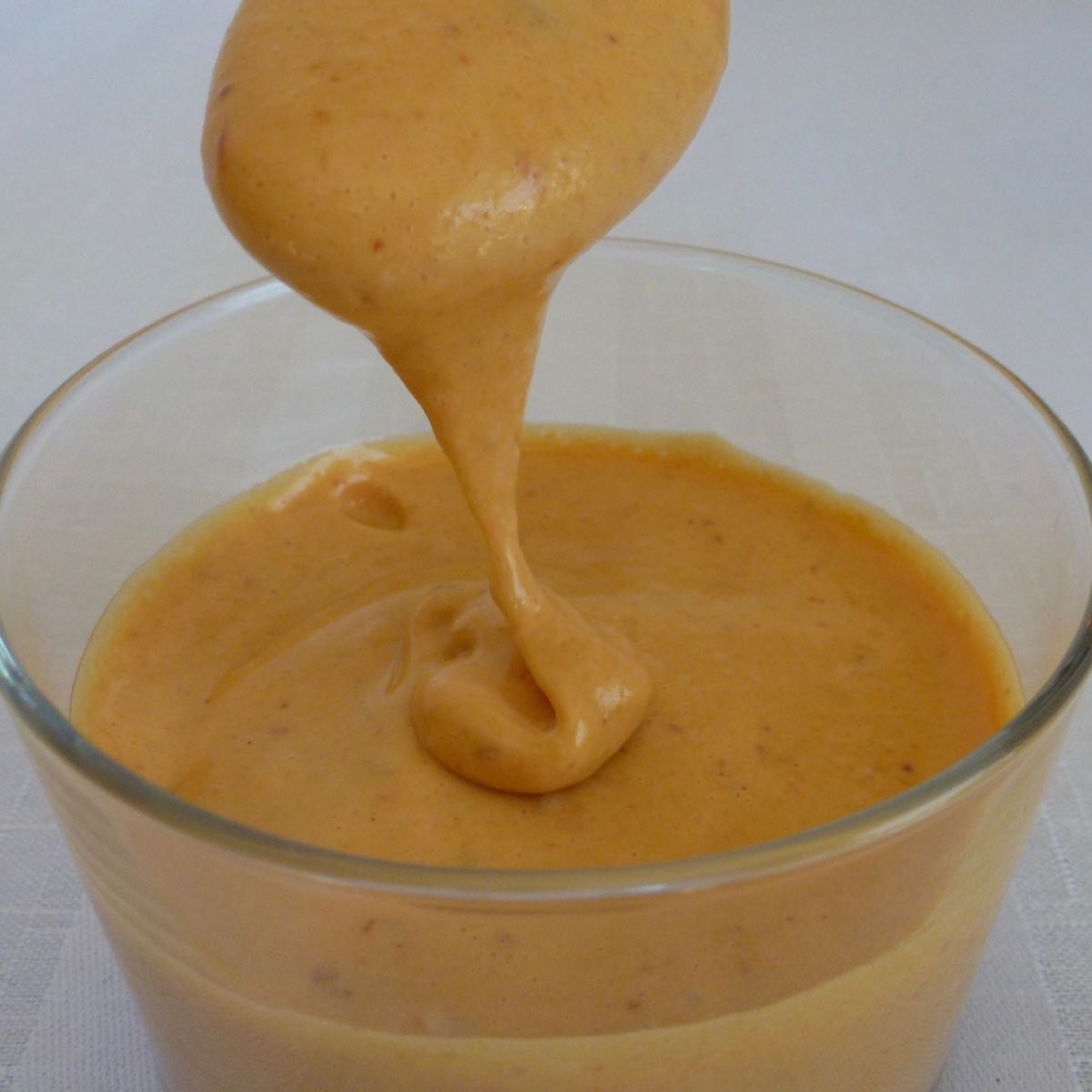 A dish of homemade Chipotle Mayo with a spoon lifting some out.