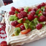 A rectangular Holiday Pavlova filled with cream and fresh strawberries, raspberries and kiwi fruit.