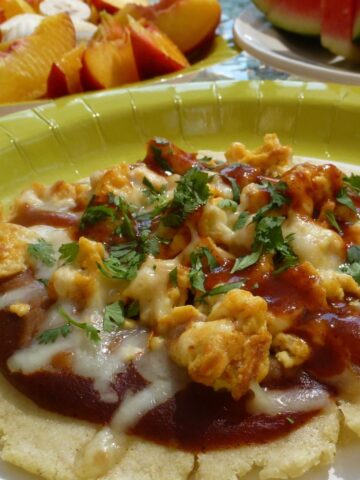 Gluten free Huevos Rancheros; a soft corn tortillas topped with enchilada sauce, scrambled eggs, cheese and a sprinkling of cilantro.