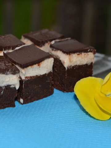 Squares of Cappuccino Brownies set on a bright blue napkin garnished with a yellow pansy.