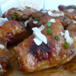 A plate of Mango Chutney Chicken sprinkled with chopped green onion and coconut flakes.