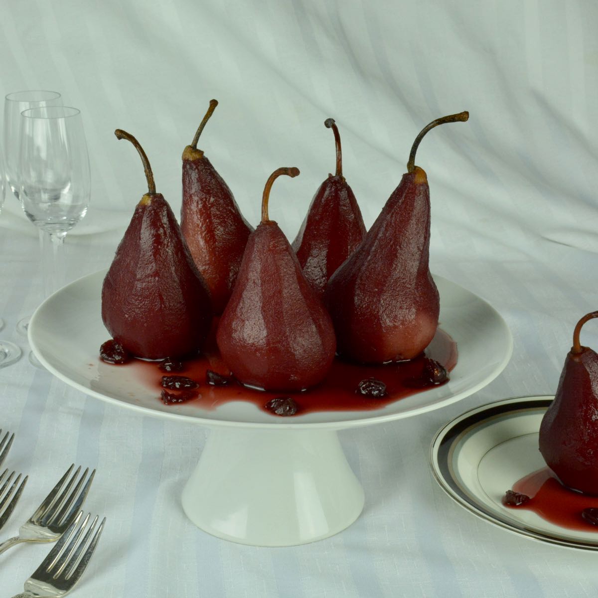 A pedestal tray with six Pears Poached in Port with Cranberries.