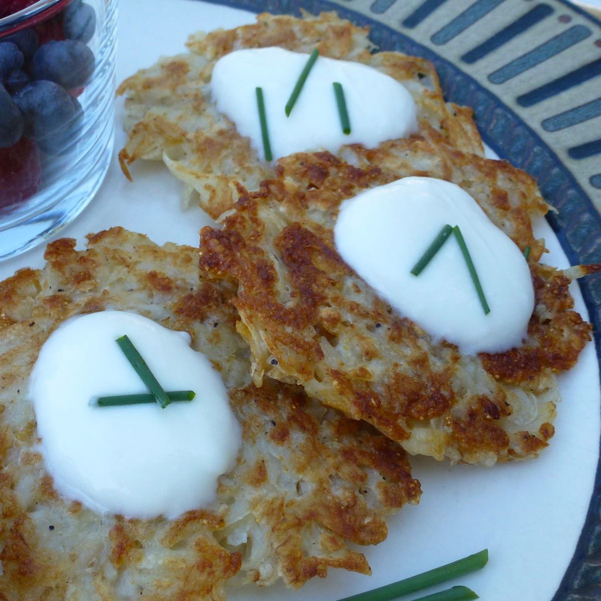 Three Potato Latkes topped with sour cream and a few snipped chives.
