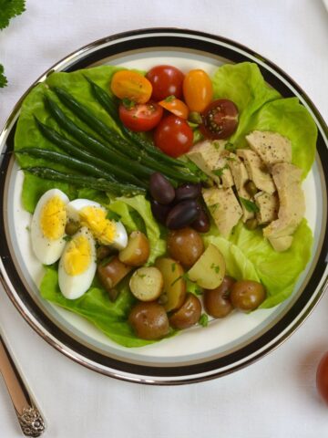 A composed Salad Nicoise: hard boiled egg, potatoes, green beans, tomatoes and canned tuna with an amazingly delicious vinaigrette dressing.