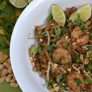 Shrimp Pad Thai topped with cilantro, chopped peanuts and lime wedges.