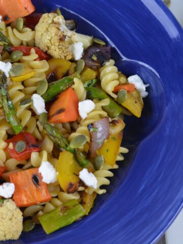 A bowl of Southwestern Grilled Vegetable Pasta topped with goat cheese and pumpkin seeds.