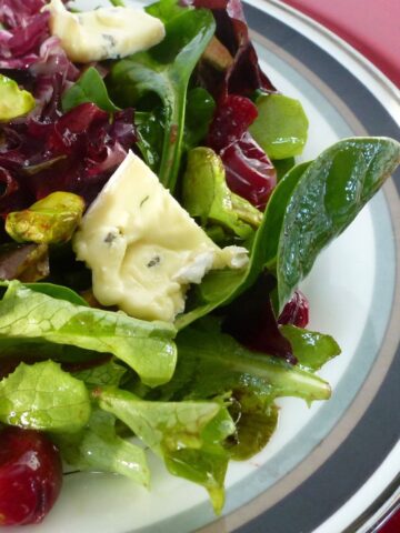 A plate of winter greens with Cranberry Port Vinaigrette, pistachio nuts and blue cheese.