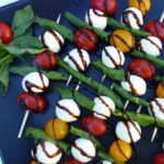 A tray of tomato bocconcini & basil skewers drizzled with balsamic glaze.
