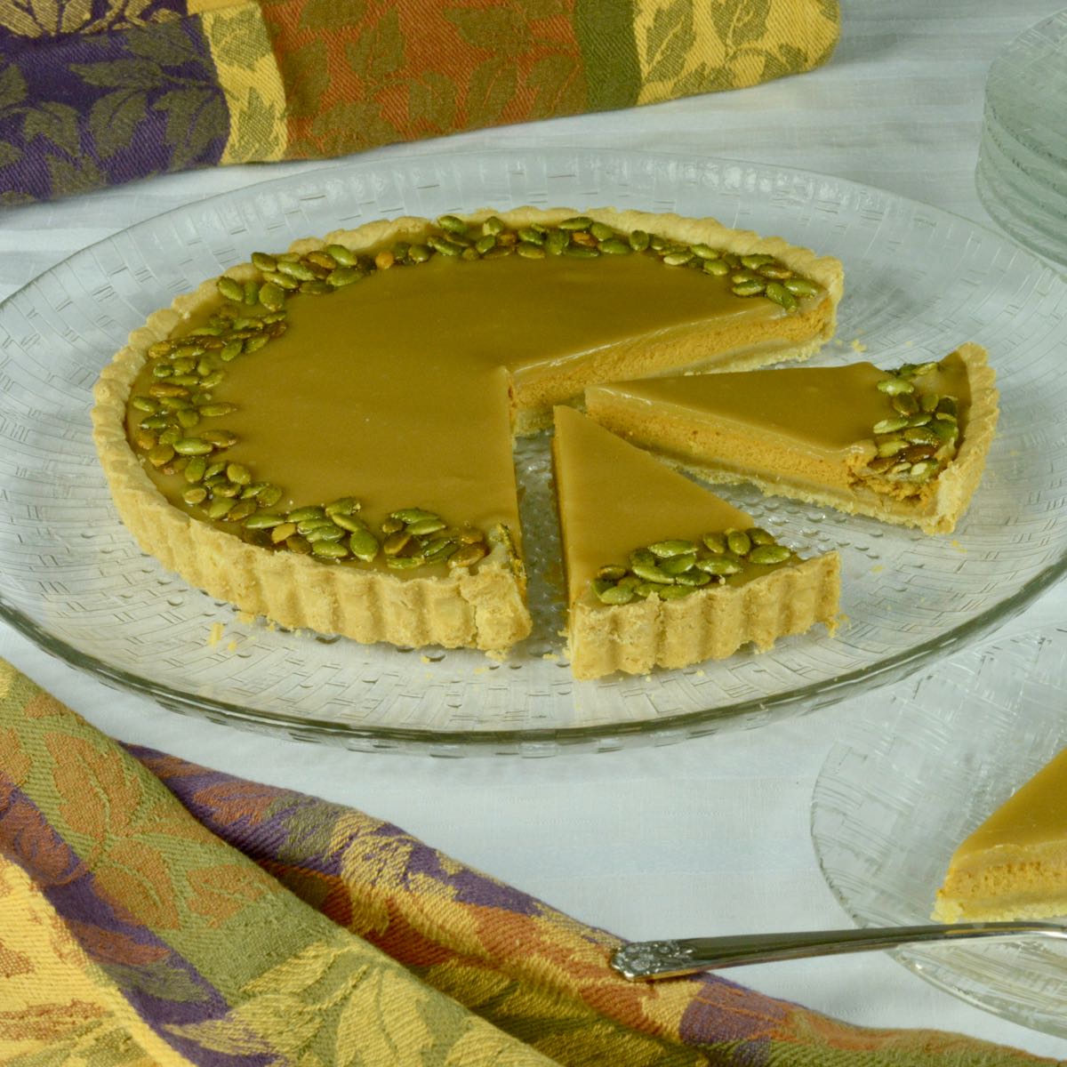 Bourbon Caramel Pumpkin Tart with two pieces cut and one served on a plate.