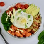 A Breakfast Power Bowl filled with cooked quinoa, avocado, spinach, tomatoes and egg and topped with hollandaise sauce for a special treat.