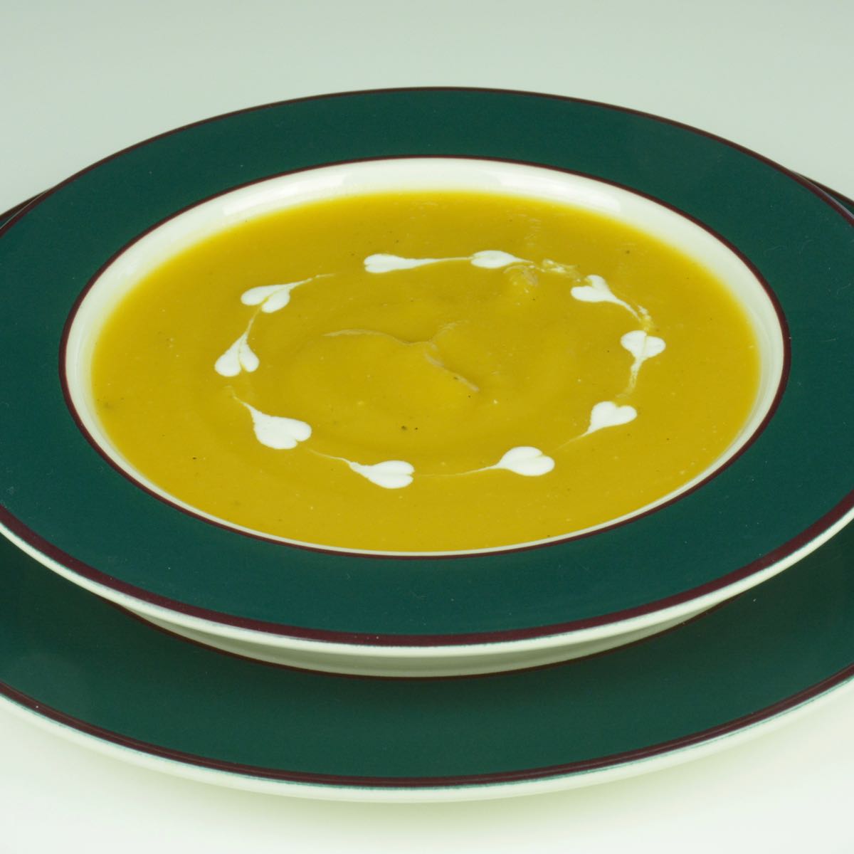 A bowl of Butternut Squash Soup with a heart design made from thinned yogurt.
