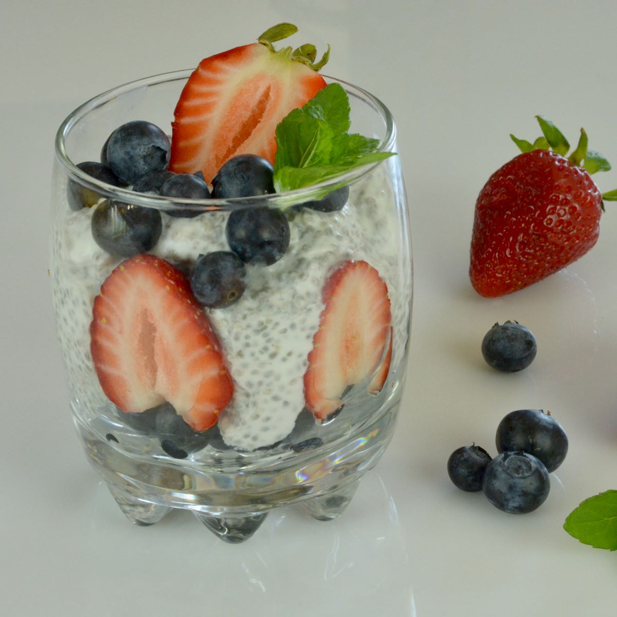 A glass of Chia Pudding with strawberries and blueberries.