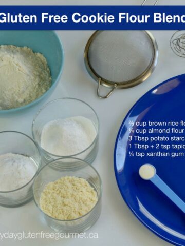 A blue plate with with the recipe in white letters, surrounded by a strainer and 4 bowls with the cookie flour ingredients.