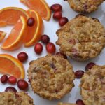 Cranberry Orange Muffins with streusel topping surrounded by orange wedges and whole cranberries.
