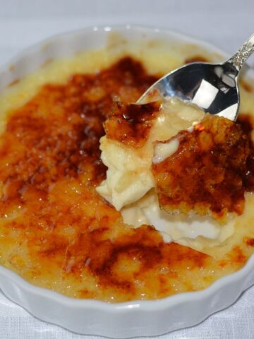 A spoonful of Creme Brulee being lifted out of a ramekin dish.