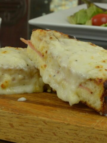 A Croque Monsieur sandwich cut in half and topped with white sauce.