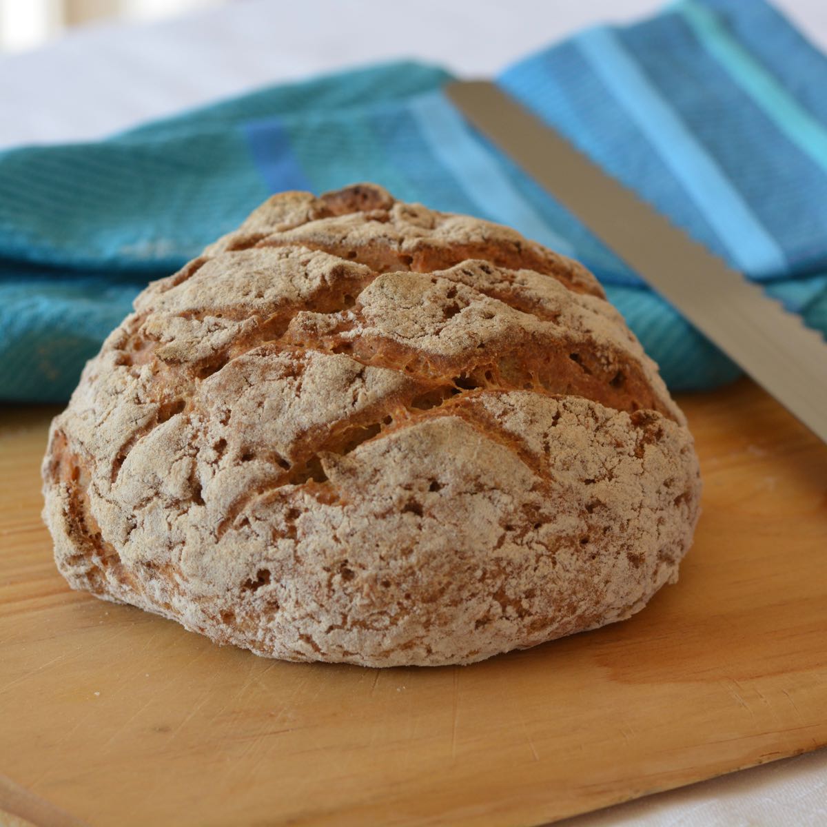 A boule of Gluten Free Crusty Bread on a cutting board.