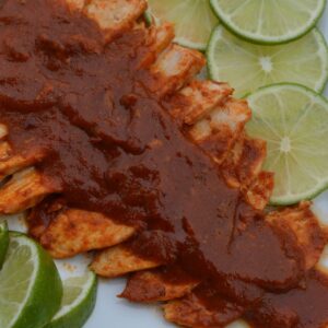 A platter of Gluten Free Cumin Lime Chicken covered with sauce and garnished with fresh lime slices.