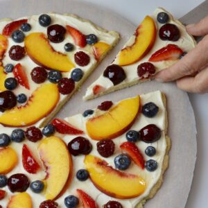 A piece being served from a Glazed Fresh Fruit Pizza.