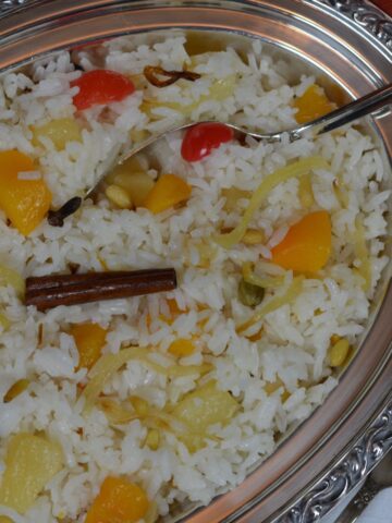 A dish of Rice Pilaf with chunks of fruit, whole spices and pine nuts.