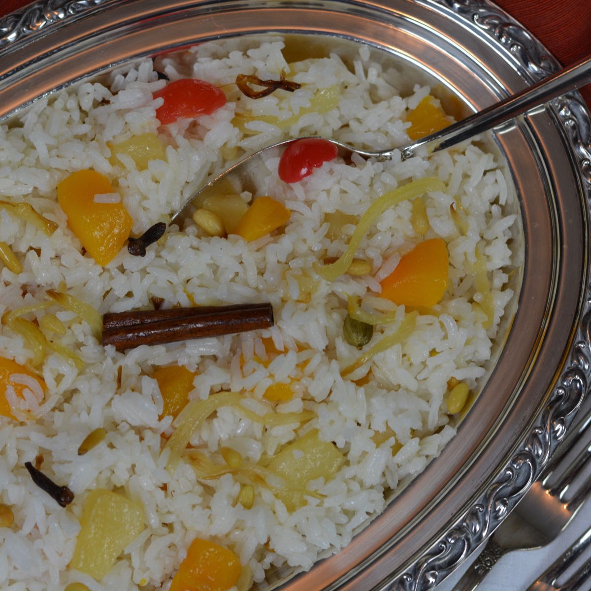 A dish of Rice Pilaf with chunks of fruit, whole spices and pine nuts.