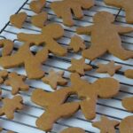 A cooling rack covered in gingerbread men, some with a heart shape space in the center.