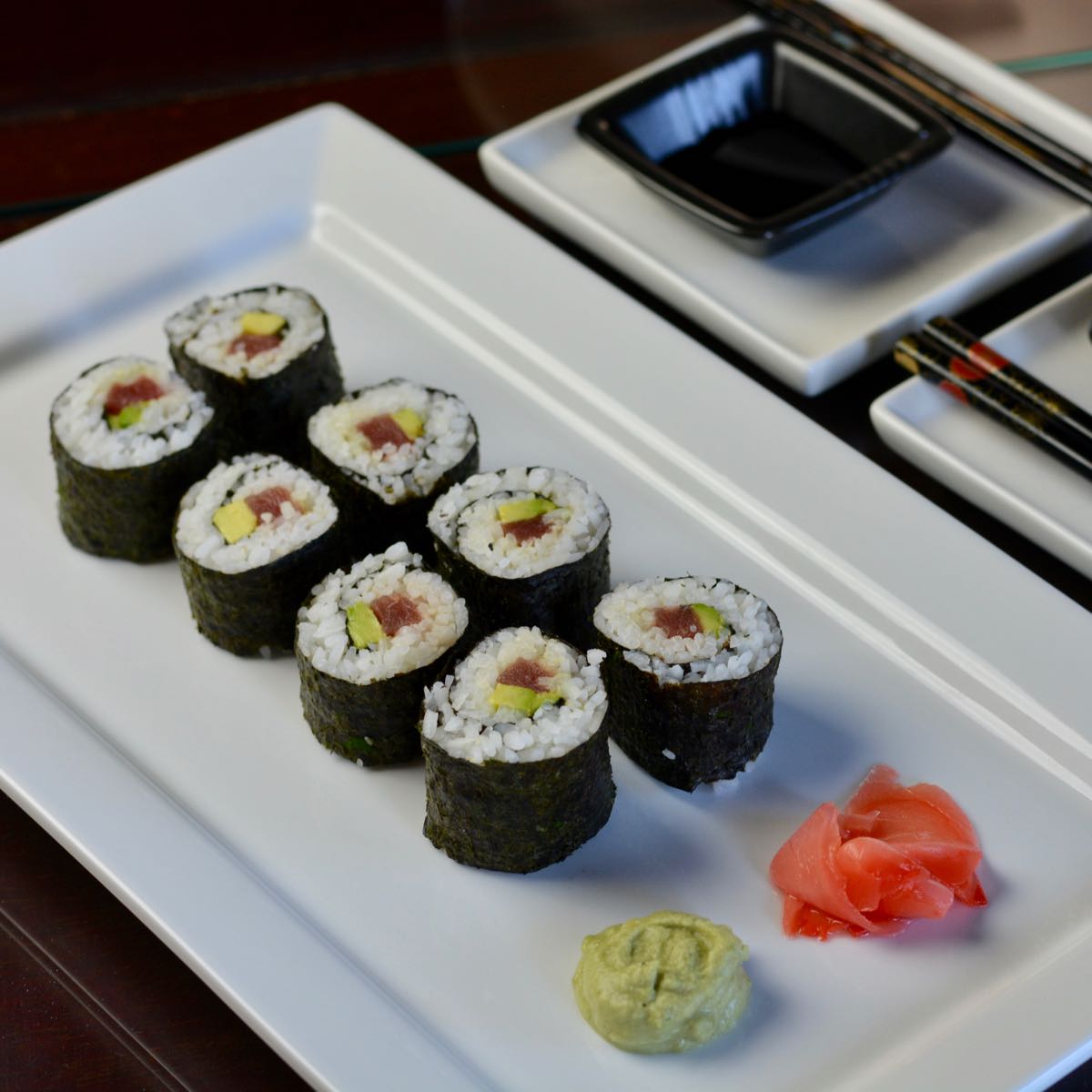 A plate with futomaki, homemade sushi rolls, with pickled ginger and wasabi.