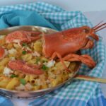 A dish of gluten free Lobster Macaroni and Cheese decorated with the head and tail of the lobster.