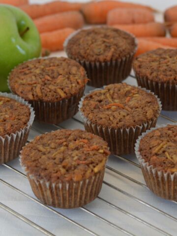 A rack of Morning Glory Muffins surrounded by carrots and apples.