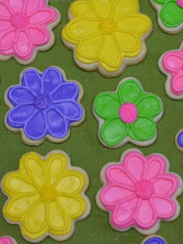 Gluten free sugar cookies shaped like flowers decorated with brightly coloured royal icing.