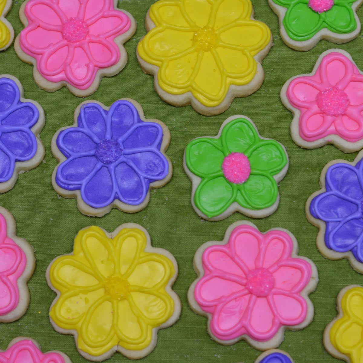 Gluten free sugar cookies shaped like flowers decorated with brightly coloured royal icing.