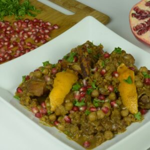 A white plate of Persian Chicken Stew sprinkled with pomegranate arils.