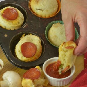 Pepperoni Pizza Cheese Buns in the pan surrounded by green pepper, mushrooms and pizza dipping sauce.