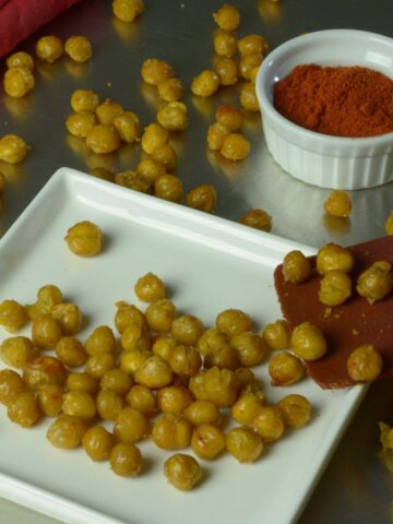 Roasted Chickpeas on a plate with a dish of paprika.