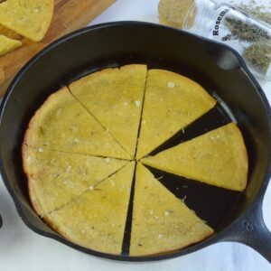 Socca, a thin, unleavened pancake made from chickpea flour; cut and ready to serve on a board with some in the frying pan..