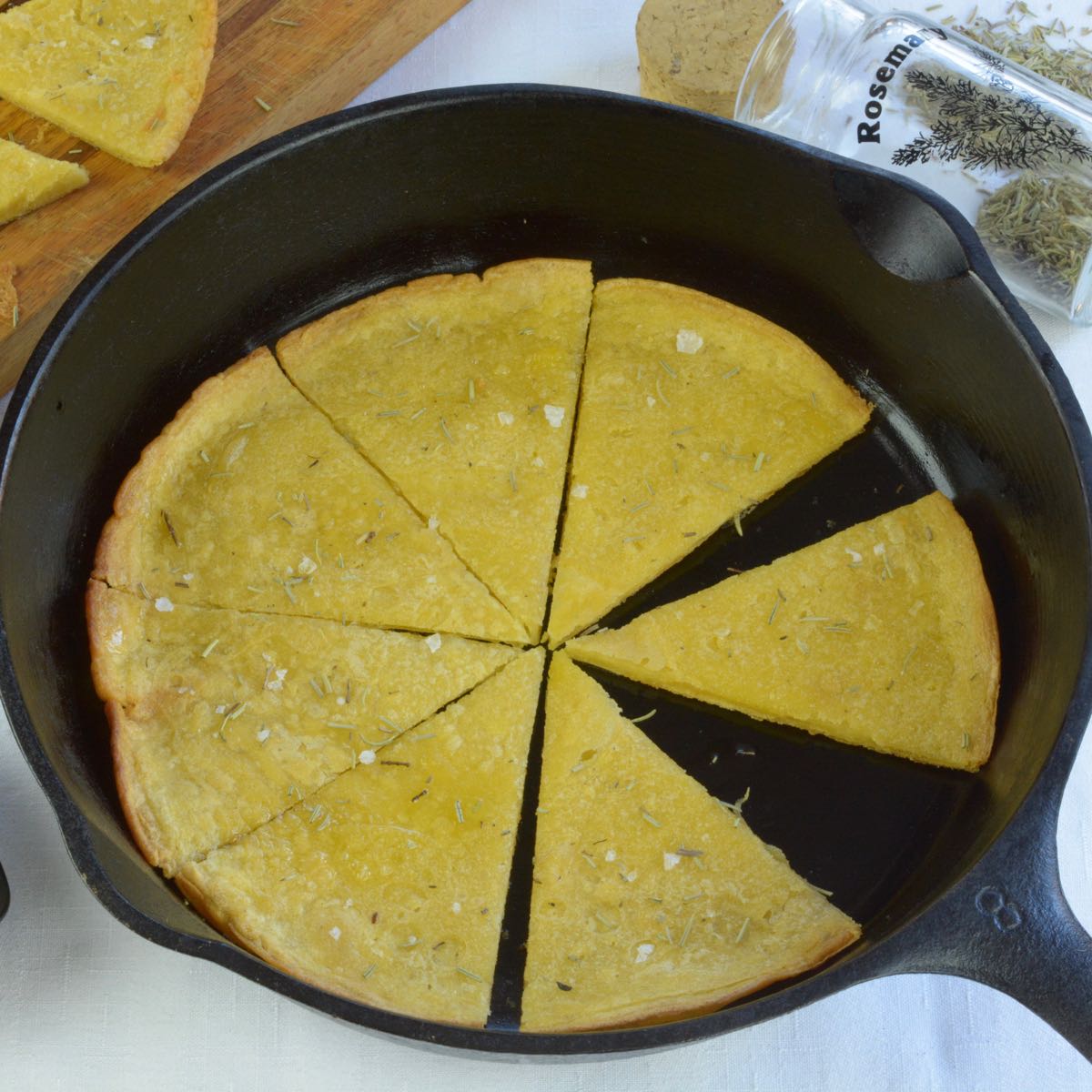 A cast iron frying pan with cooked socca cut in wedges.