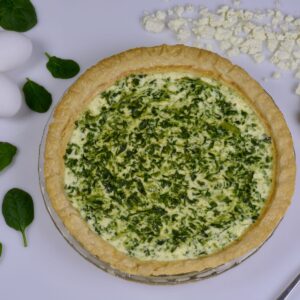 A 9-inch round Spinach Feta Quiche ready to be cut and served.