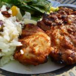 Gluten Free Tandoori Chicken on a plate beside fruited rice pilaf and a spinach salad with mango chutney dressing.