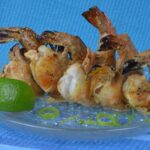 A plate of Grilled Tandoori Shrimp with fresh lime wedges.