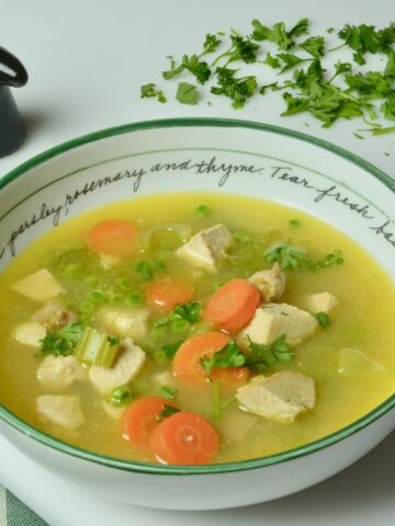 A full bowl of homemade Turkey Soup with carrots and peas.