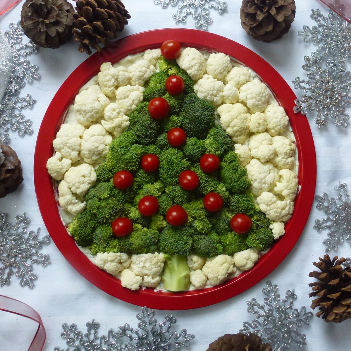 Vegetable and Dip Christmas tree made with broccoli, cauliflower and cherry tomatoes all set on top of a platter with dip.