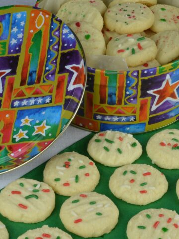 A tin of gluten free Whipped Shortbread decorated with red and green sprinkles.
